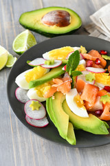 Salad with organic avocado and with salmon, eggs and radish. Decorated with mint leaf and pomegranate. Healthy lunch, vegetarian food, diet dish. food for weight loss. Selective focus and copy space