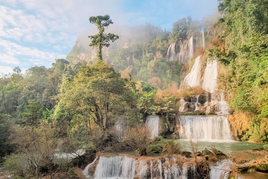 Thi Lo Su Waterfall (Umphang), beautiful silky water flowing from top of green mountain around with green forest and blue sky background, the largest waterfall in Thailand, Umphang, Tak, Thailand.