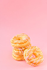 a lot of donuts, breakfast concept, the concept of calorie unhealthy diet, obesity, fat, pink background, selective focus