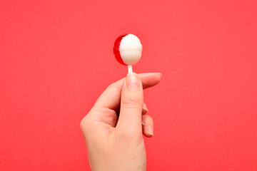 Lollipop in female hand on red background. Space for text or design.