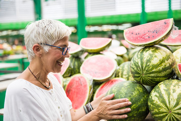 Senior woman buying watermelon on market