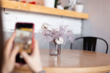 a photo of the process of creating a mobile photo that depicts various objects and flowers that are laid out on the table in a modern style. selective focus