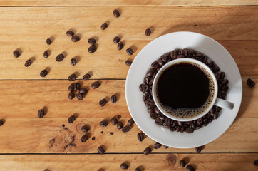 White cup of coffee with beans on table, top view.