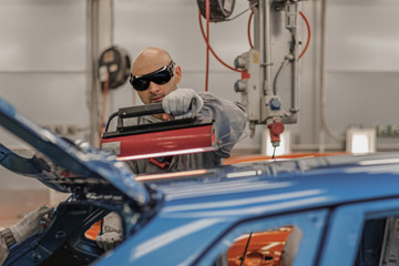 Fototapeta premium The worker of shop of coloring carries out drying of a varnish by means of a special lamp