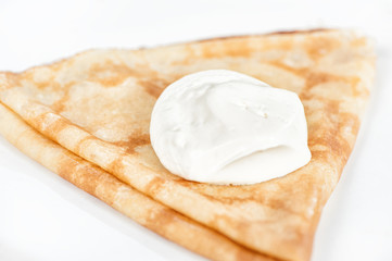 Thin delicious pancake with sour cream on white