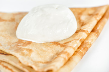 Thin delicious pancake with sour cream on white