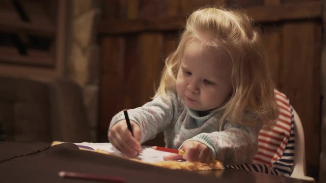 Little girl child draws with a pencil.