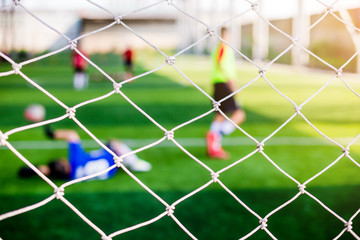 Mesh of goal with blurry of soccer goalkeeper and soccer players
