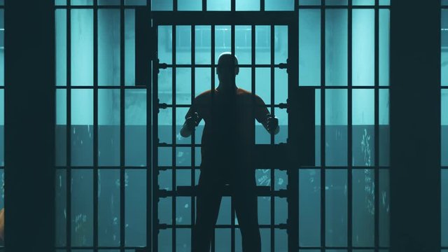 Rows of one person dark prison cells. Adult criminals captured behind iron bars
