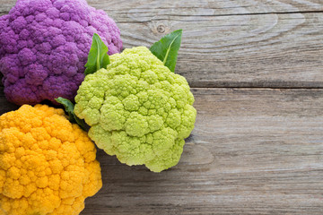 Rainbow of eco cauliflower on the wooden table.