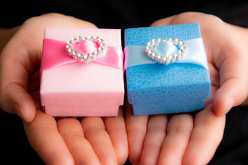 Hands holding craft gift blue and pink boxes