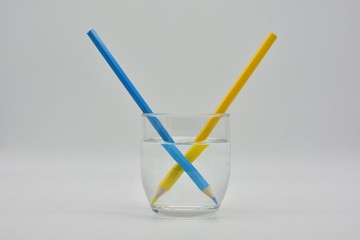 Refracción de la luz, demostrada en un vaso de agua con lápices de colores