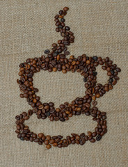 A cup and saucer of coffee beans. Whole bean coffee. Coffee cup on burlap