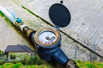 Water meter on concrete with home and green nature background, Measuring device, Open cover of water meter to check counter number of water consumption, water pipe and meter with waterspout of home