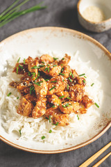 Sesame chicken pieces with rice on a ceramic plate. Chinese traditional dish.