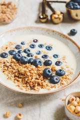 Healthy breakfast, a bowl with organic granola, chocolate pieces, fresh blueberries, hazelnuts and soya milk.