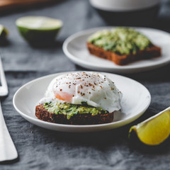 Avocado sandwich with rye bread and a poached egg on a plate. The concept of healthy balanced breakfast.