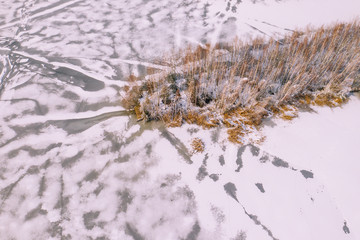 Aerial view of the winter snow covered forest and frozen lake from above captured with a drone.