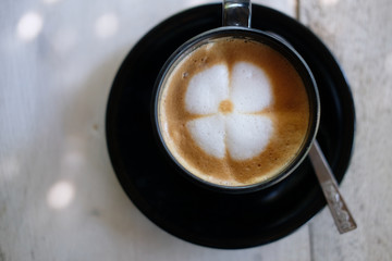 cappuccino coffee with flower latte art on wooden desk