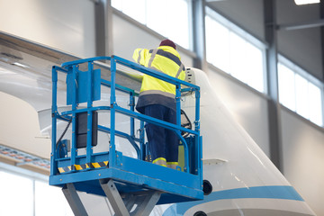 Worker repair airplane while standing on scissor lift