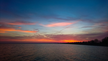 A dramatic and colorful sky during sunset on the water