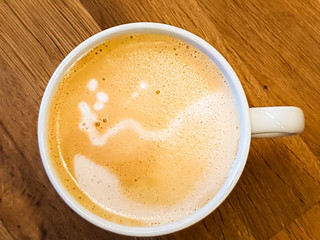A vegan cappuccino with oat milk on a wooden table, top view