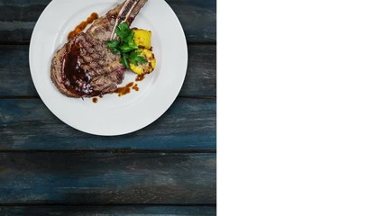 Rib-eye steak with corn rotating on a white plate. Top view on a wooden background. Square layout for social networks and copy space for your text