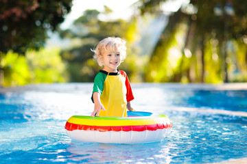 Child in swimming pool on toy ring. Kids swim.