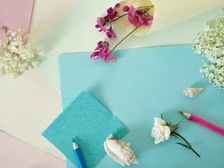 On a light background, top view, empty color paper for notes, pencils, flower buds, concept congratulations, preparation for romantic holidays, women's day, mother's day