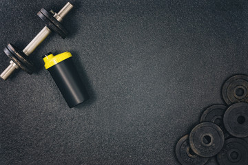 Obraz na płótnie Canvas Fitness or bodybuilding concept background. Product photograph of old iron dumbbells on black grey, conrete floor in the gym. Photograph taken from above, top view with lots of copy space