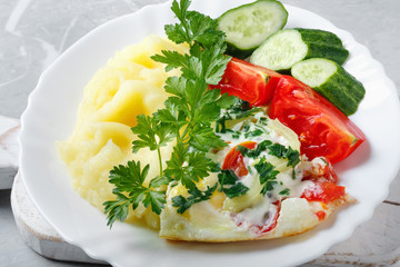 Hot tasty mashed potatoes with scrambled eggs, tomatoes, cucumbers and fresh parsley