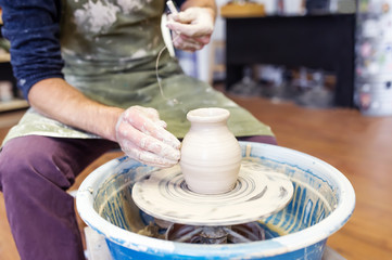 Potter giving shape to his vase on the wheal.