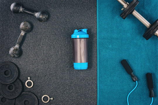 Fitness or bodybuilding concept background. Product photograph of old iron dumbbells on black grey, conrete floor in the gym. Photograph taken from above, top view with lots of copy space