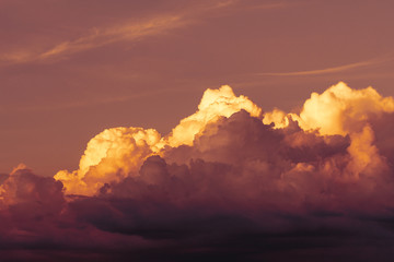 Dramatic view of a dark clouds in the evening sky illuminated by sunset