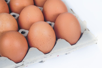 Raw chicken eggs in egg box on white background.