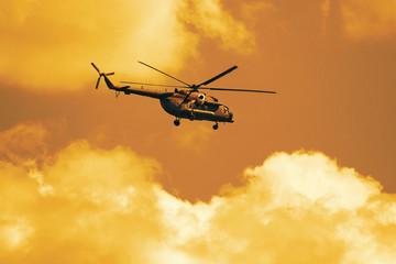 Dramatic view on the military helicopter in the red sunset sky