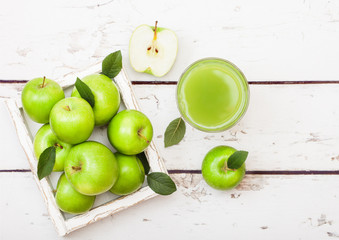Glass of fresh organic apple juice with green apples in box on wooden background