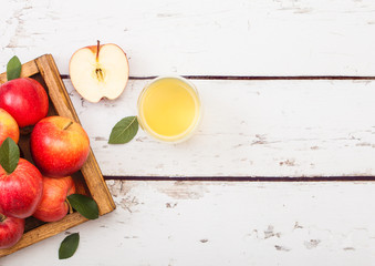 Glass of fresh organic apple juice with red apples in vintage box on wooden background.Space for text