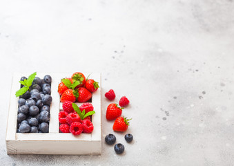 Naklejka na ściany i meble Fresh raw organic berries in white vintage wooden box on kitchen table background. Space for text. Top view. Strawberry, Raspberry, Blueberry and Mint leaf