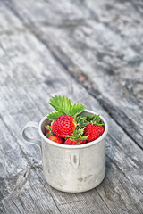 Summer joy. Ripe strawberries in a mug on the background of old boards