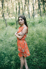 Beautiful young girl in a summer red dress in a park