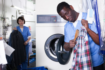 Man dry cleaning clothes in laundry