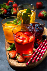 fruit and berry beverages in assortment on dark background, vertical top view