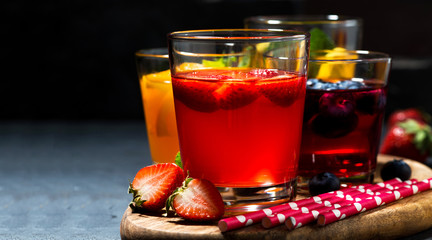 fruit and berry beverages in assortment on dark background