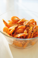 Shrimp food in a bowl. Portion of boiled shrimp in a transparent plate on the table. 