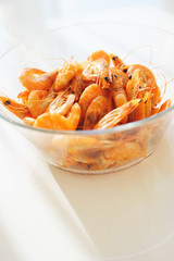 Shrimp food in a bowl. Portion of boiled shrimp in a transparent plate on the table. 
