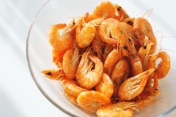 Shrimp food in a bowl. Portion of boiled shrimp in a transparent plate on the table. 