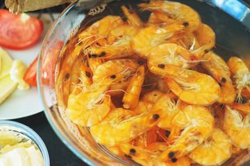 Shrimp food in a bowl. Portion of boiled shrimp in a transparent plate on the table. 