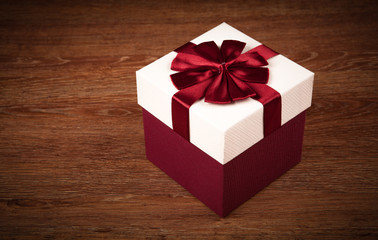 white box with red bow on a wooden background