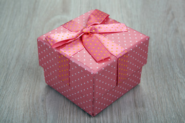 pink gift box with a bow on a gray wooden background